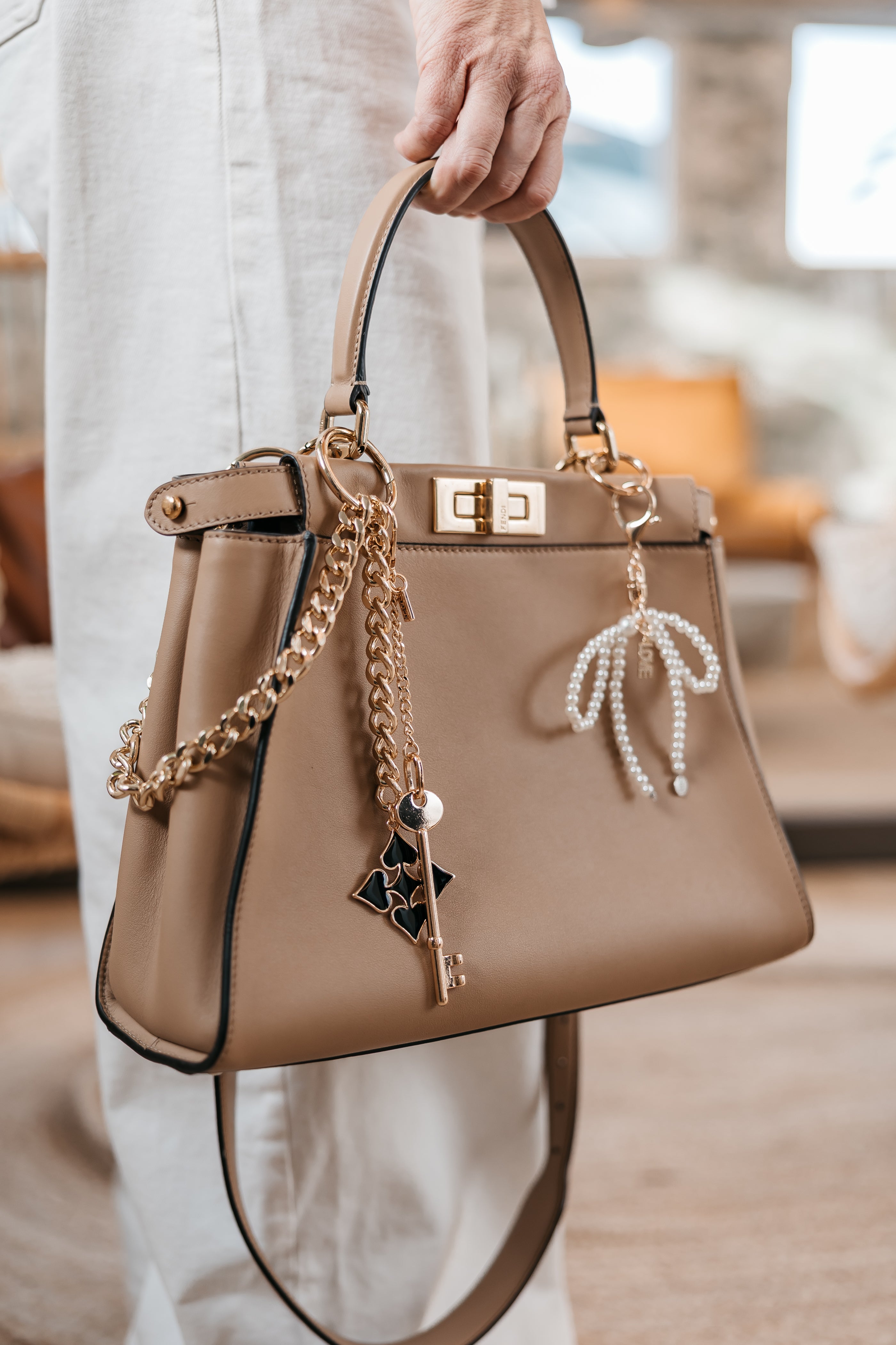 Beige handbag with decorative chain and bow charm jane the brand.