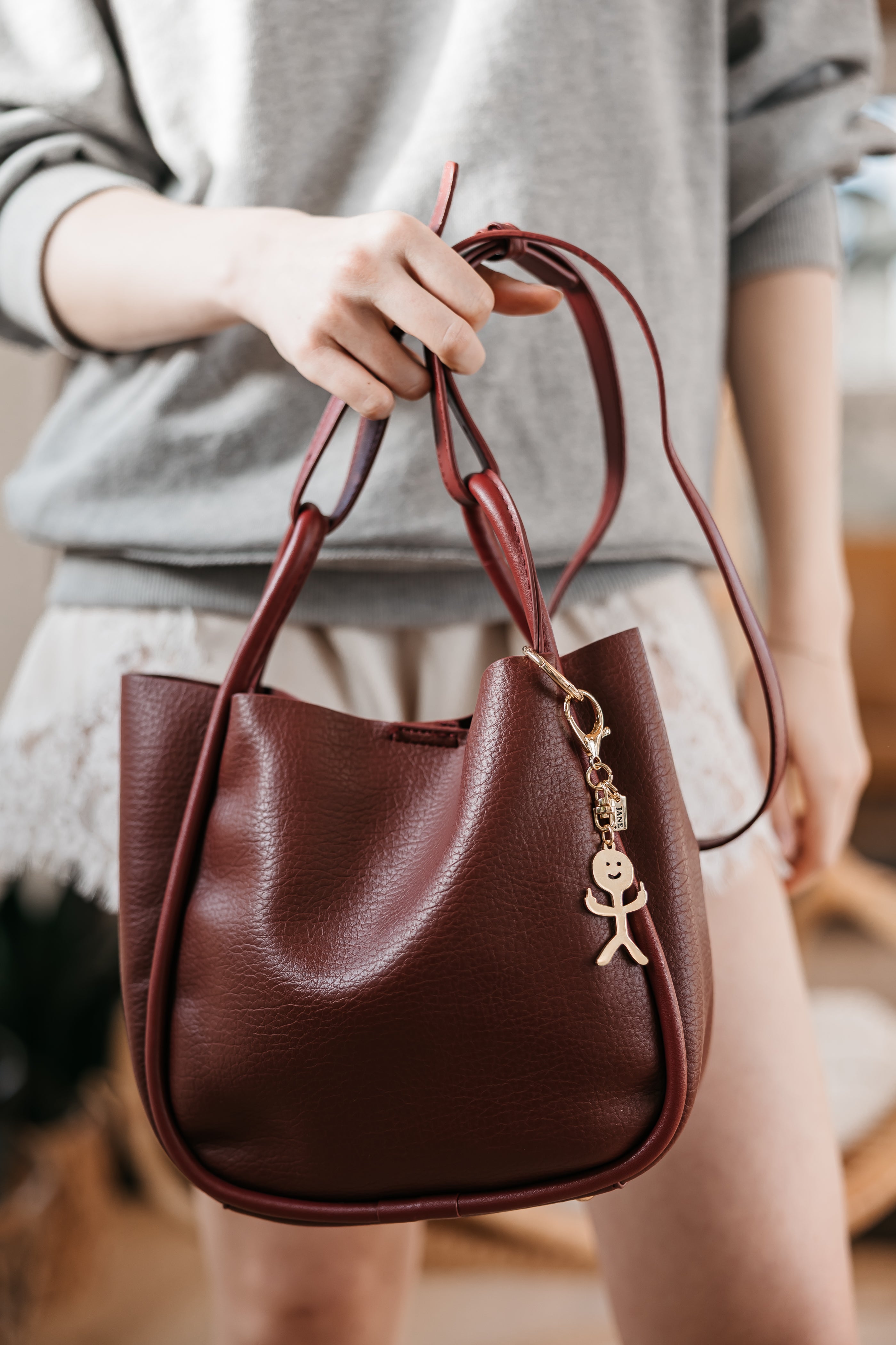 Brown handbag held by a person wearing a gray sweater.