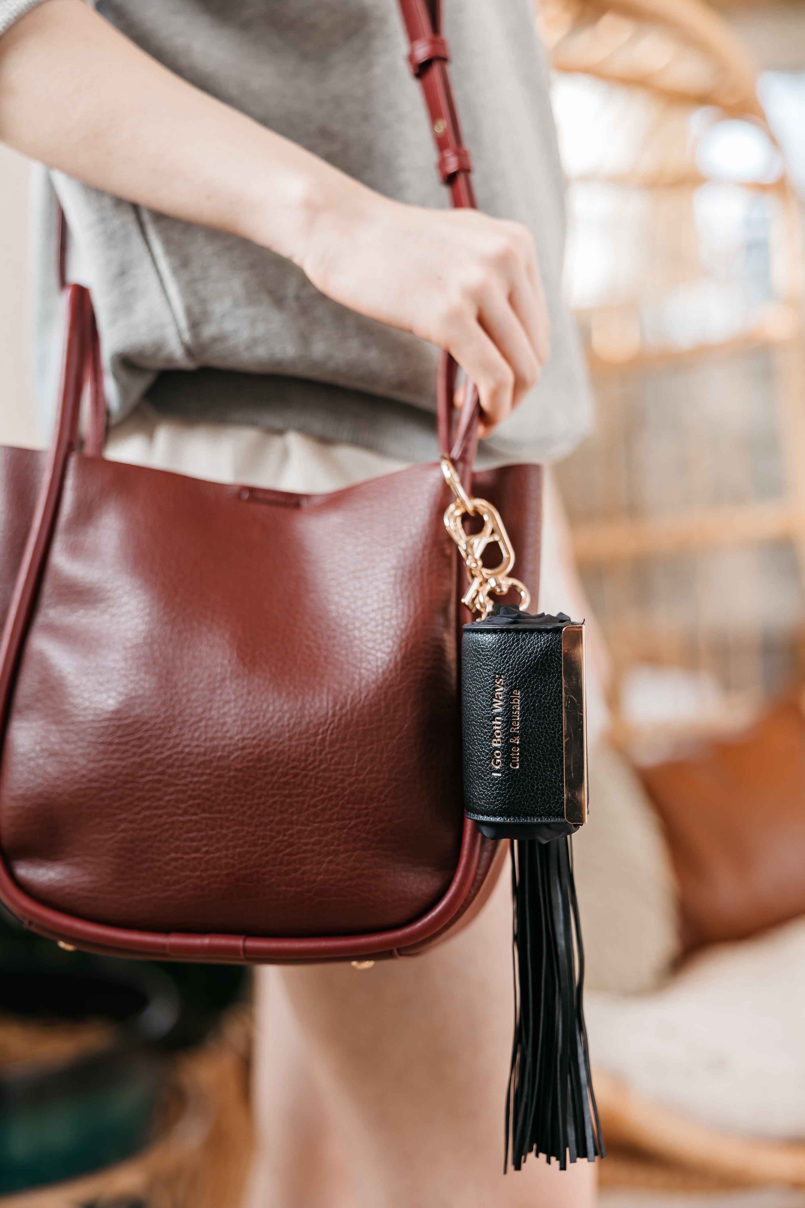 Brown leather handbag with a tassel detail held by a person.