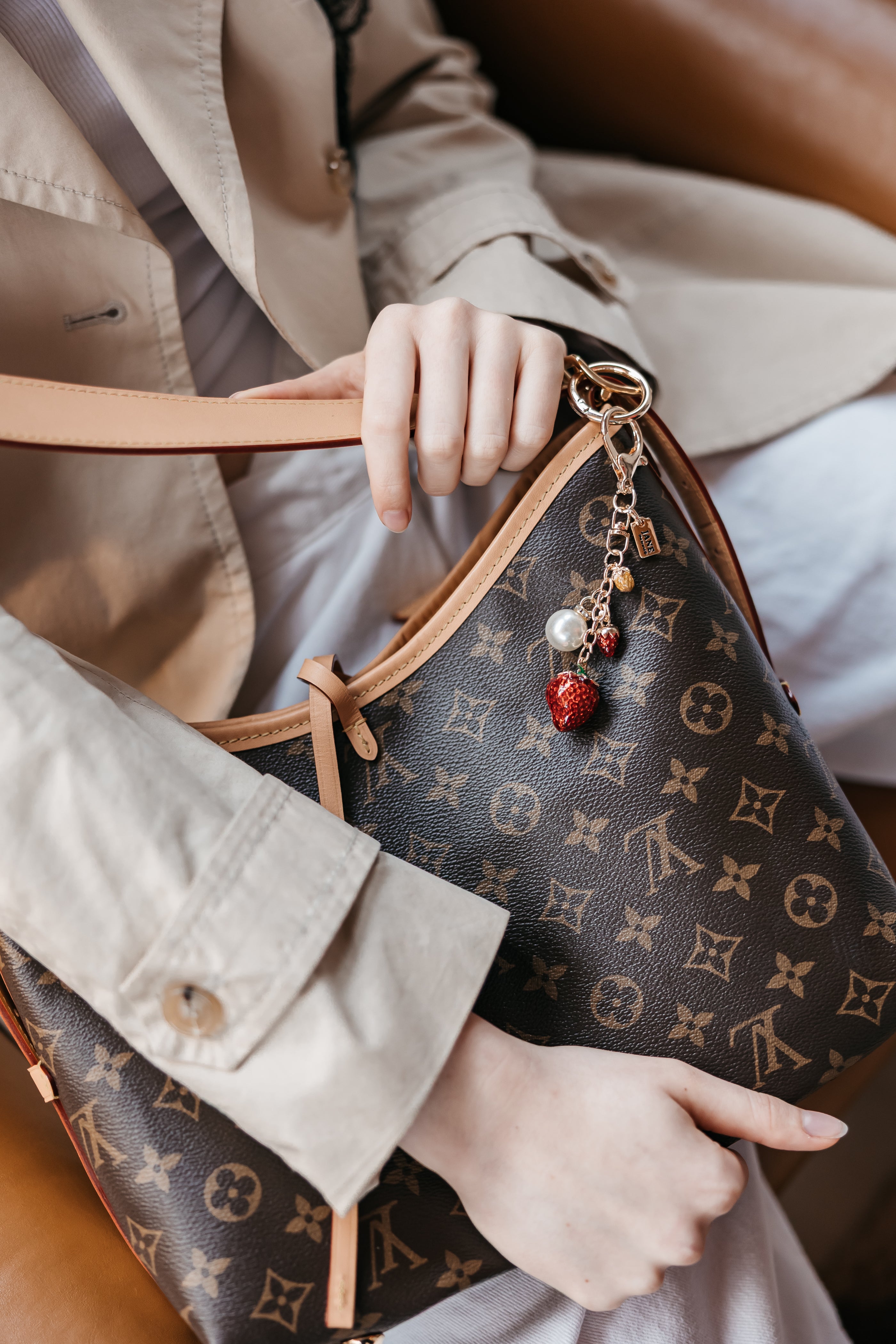 Person holding a purse with strawberry charm