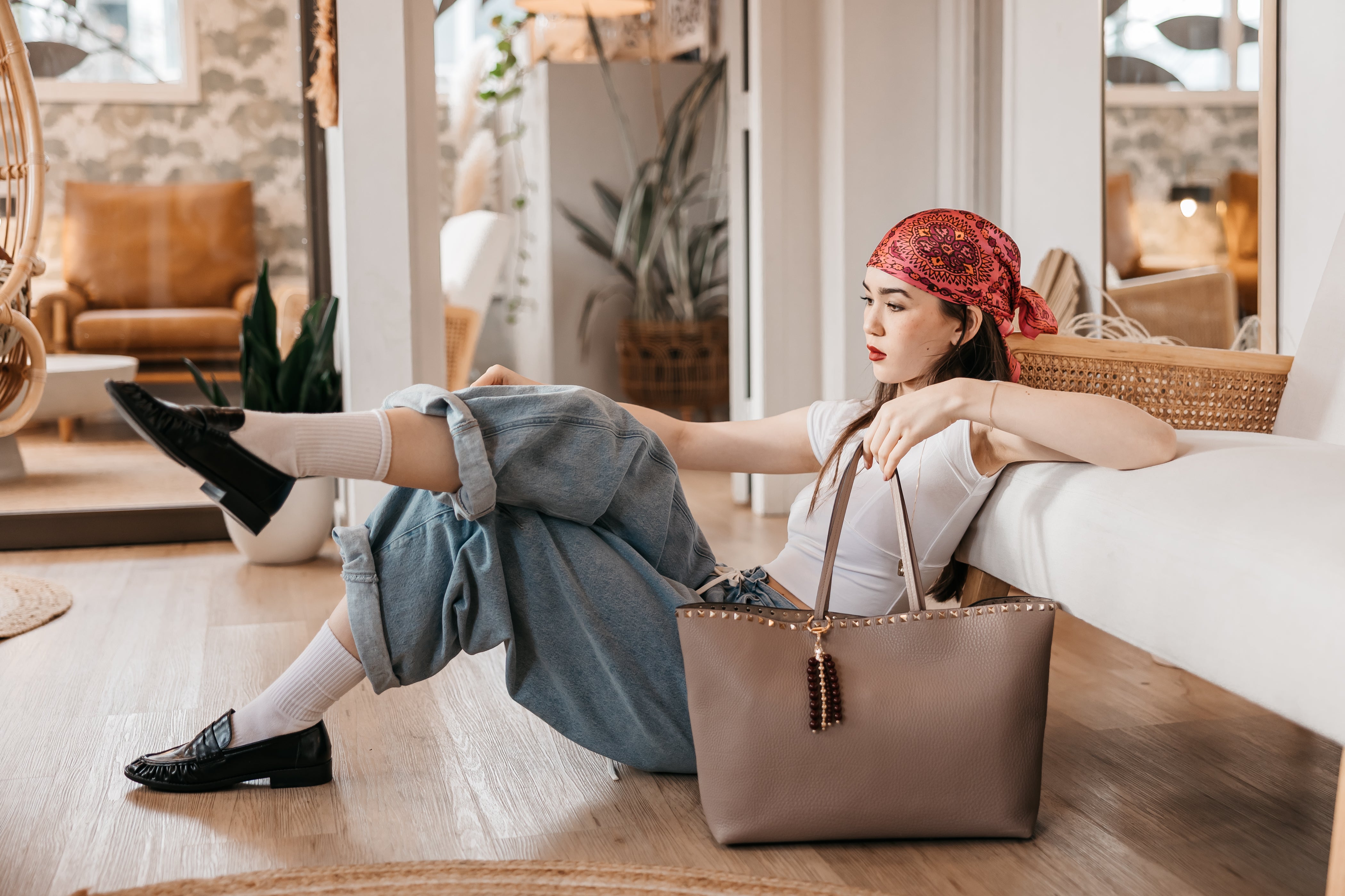Woman sitting on a couch with a brown handbag purse charm