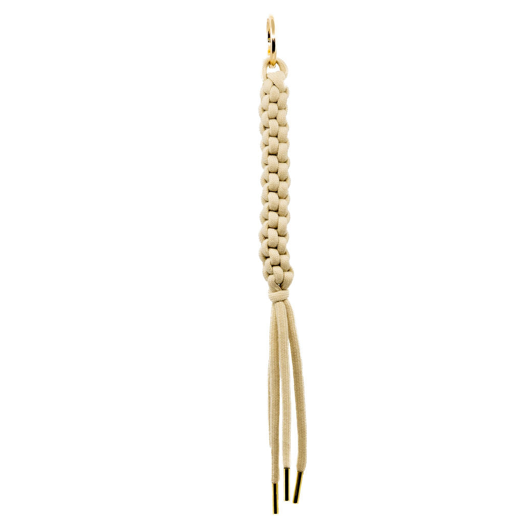 A minimalist’s dream, this cream braided tassel charm with gold ends offers subtle texture and clean lines. Made from durable cotton cord, it brings a soft yet structured accent to any bag.&nbsp;&nbsp;