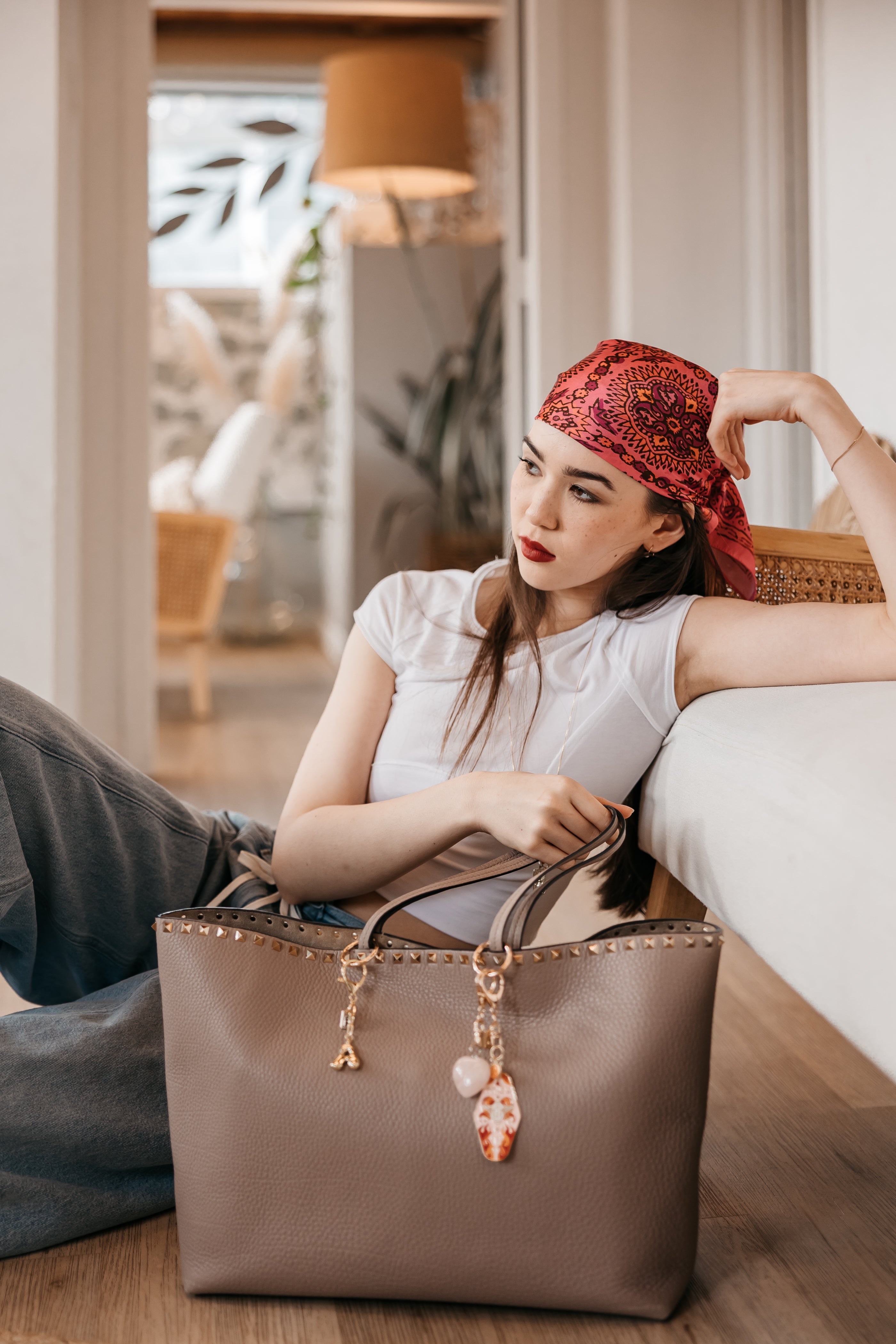 Woman with a red headscarf sitting purse charms bubble letter charms zodiac charms on purse.