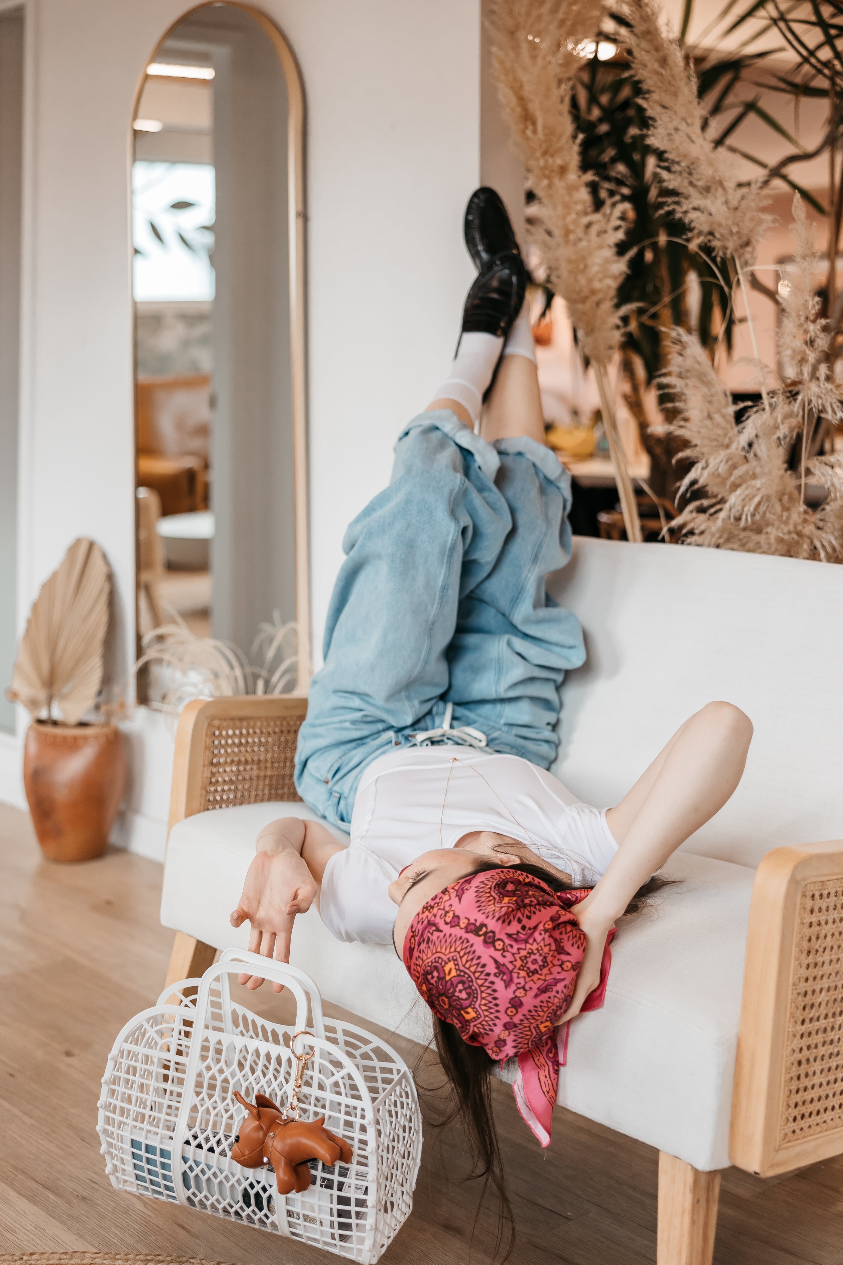 Person sitting on a white couch with a white basket holding a purse with bulldog charm