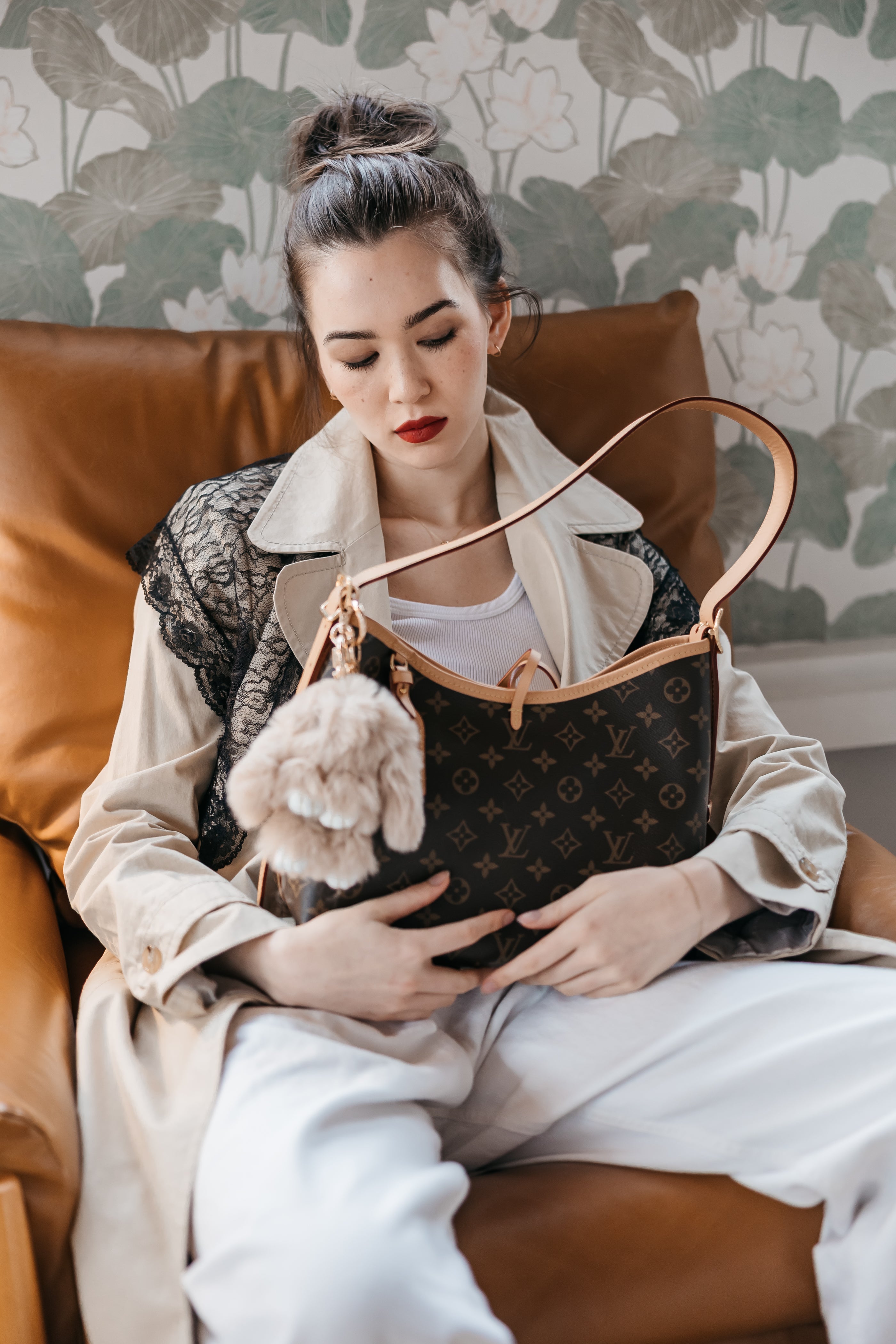 plush bunny charm on designer bag, women in chair with bag
