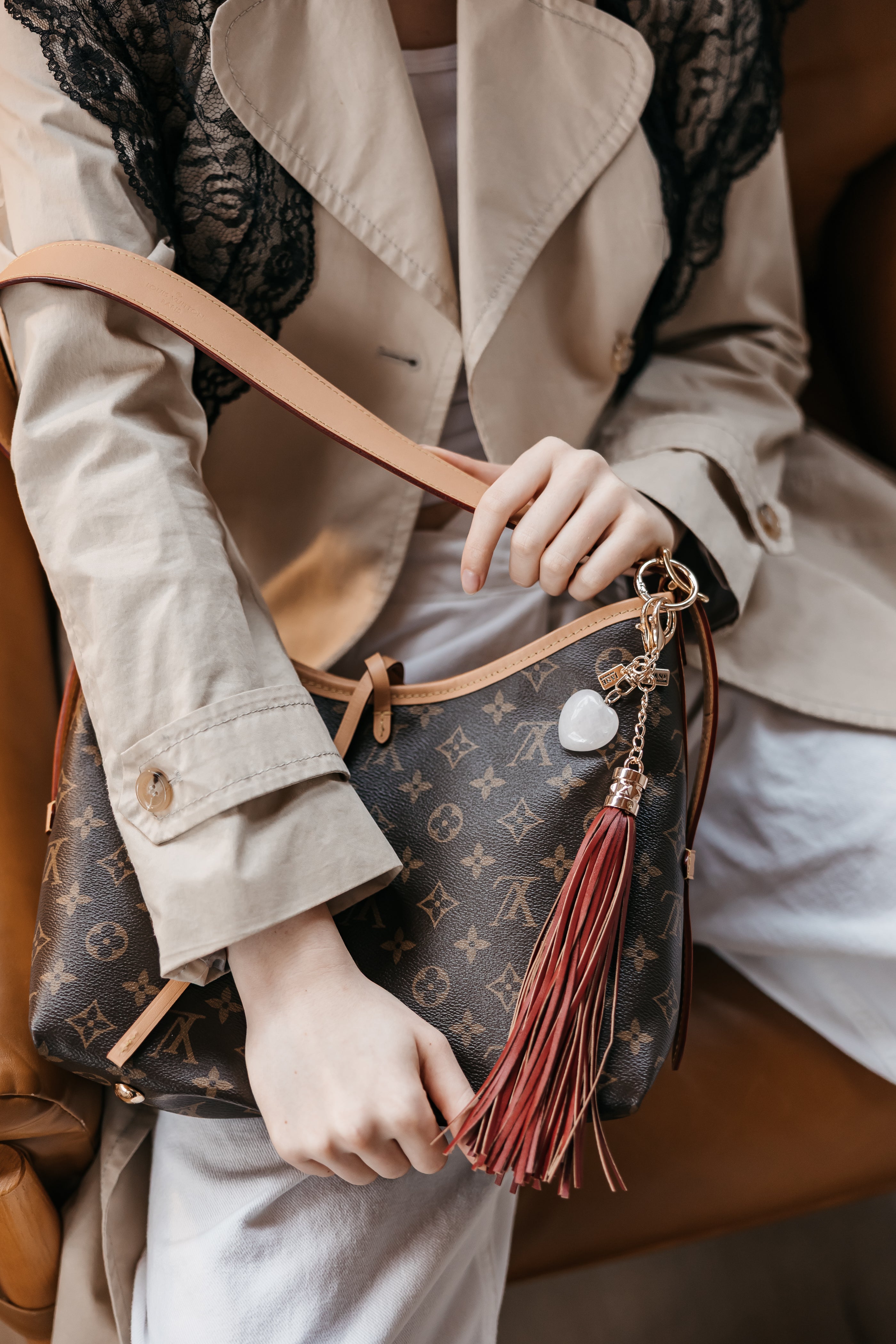 Person holding a Louis Vuitton handbag with a tassel detail